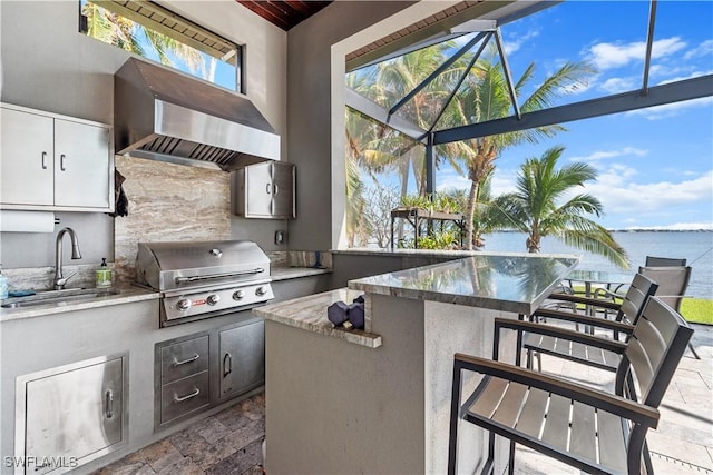 view of patio with a water view, area for grilling, glass enclosure, and an outdoor wet bar