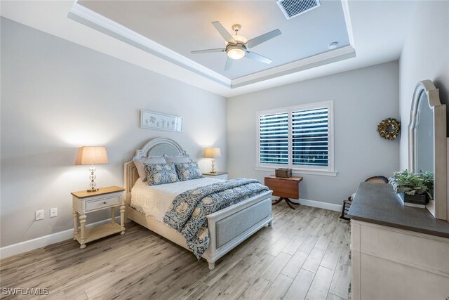 bedroom featuring hardwood / wood-style flooring, ceiling fan, and a tray ceiling