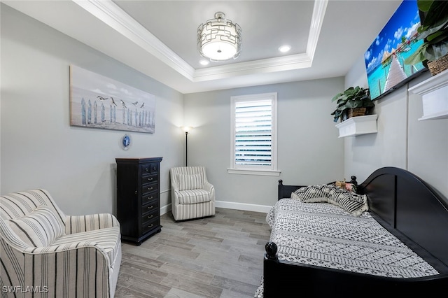 bedroom featuring ornamental molding, a tray ceiling, and light hardwood / wood-style floors