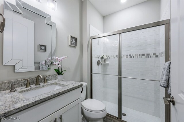 bathroom with toilet, an enclosed shower, vanity, and hardwood / wood-style floors