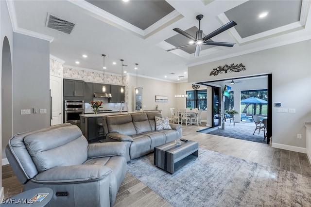 living room with light wood-type flooring, coffered ceiling, ceiling fan, and crown molding