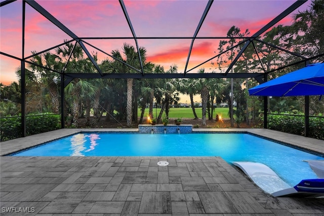 pool at dusk featuring a patio, glass enclosure, and pool water feature