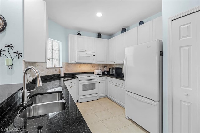 kitchen with white appliances, light tile patterned floors, dark stone counters, white cabinets, and sink