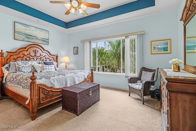 bedroom with ceiling fan, a raised ceiling, and light carpet