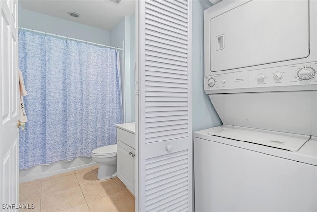 laundry area with light tile patterned floors and stacked washer / dryer