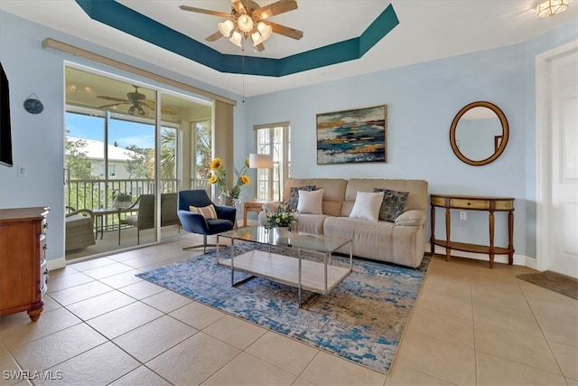 living room featuring ceiling fan, a raised ceiling, plenty of natural light, and light tile patterned floors