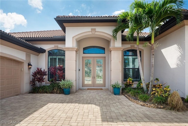 23083 Sanabria Loop, Bonita Springs, FL 34135 - view of exterior entry featuring french doors, driveway, a tile roof, a garage, and stucco siding