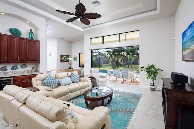 living room with wine cooler, a high ceiling, a tray ceiling, and ceiling fan