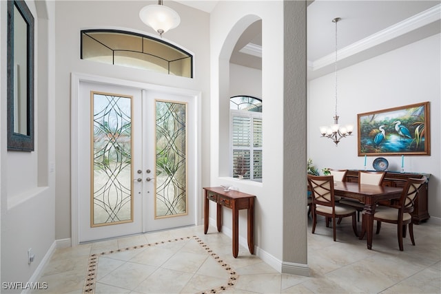 foyer entrance with french doors, a chandelier, crown molding, and light tile patterned flooring