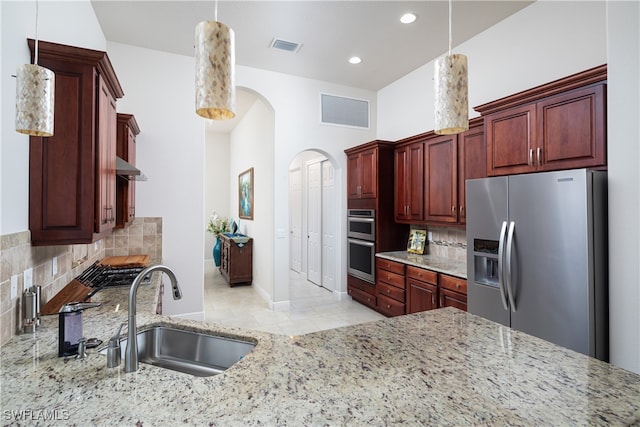 kitchen featuring stainless steel appliances, light tile patterned floors, tasteful backsplash, sink, and decorative light fixtures