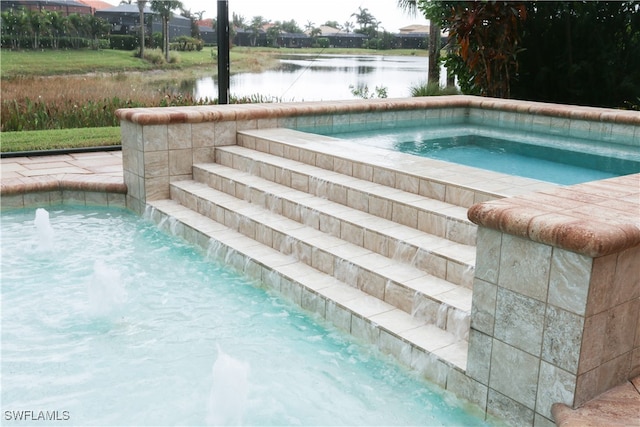 view of pool with an in ground hot tub, a water view, and pool water feature