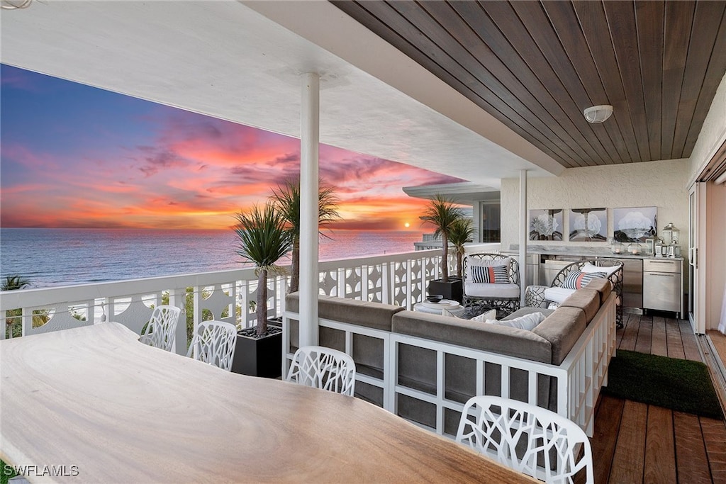 deck at dusk featuring a view of the beach, a water view, and an outdoor living space