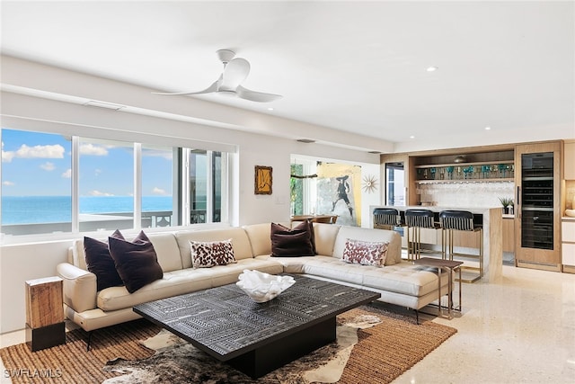 living room with a water view, bar, and ceiling fan