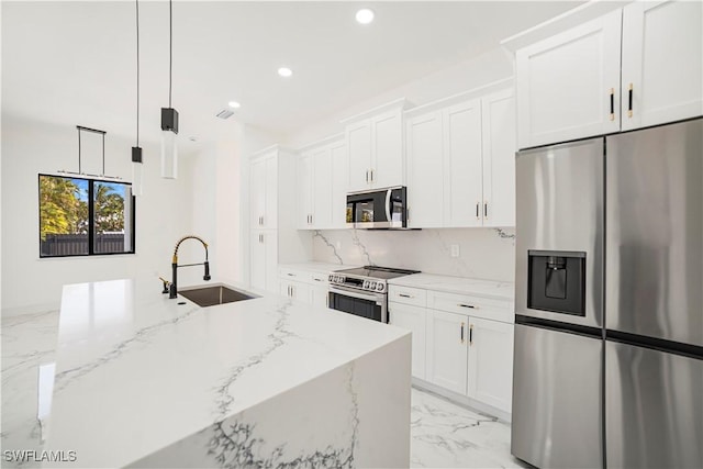 kitchen with white cabinets, light stone counters, hanging light fixtures, and appliances with stainless steel finishes