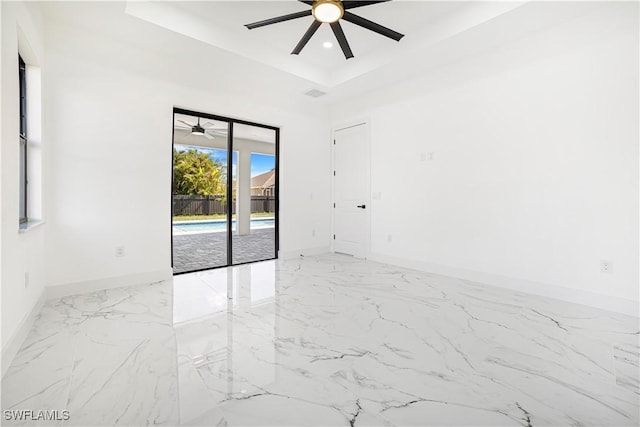 unfurnished room featuring ceiling fan and a raised ceiling