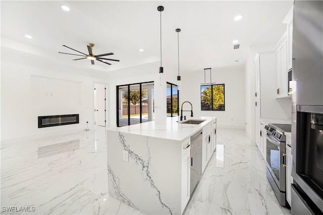 kitchen featuring a kitchen island with sink, white cabinets, pendant lighting, and appliances with stainless steel finishes