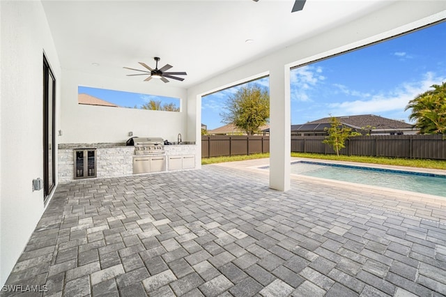 view of patio / terrace featuring an outdoor kitchen, beverage cooler, ceiling fan, grilling area, and a fenced in pool