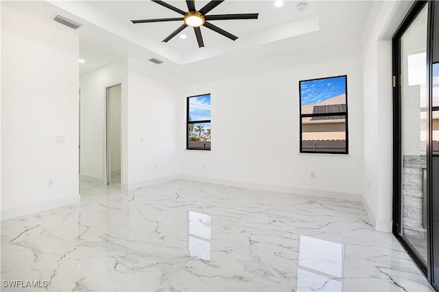 spare room with ceiling fan and a tray ceiling