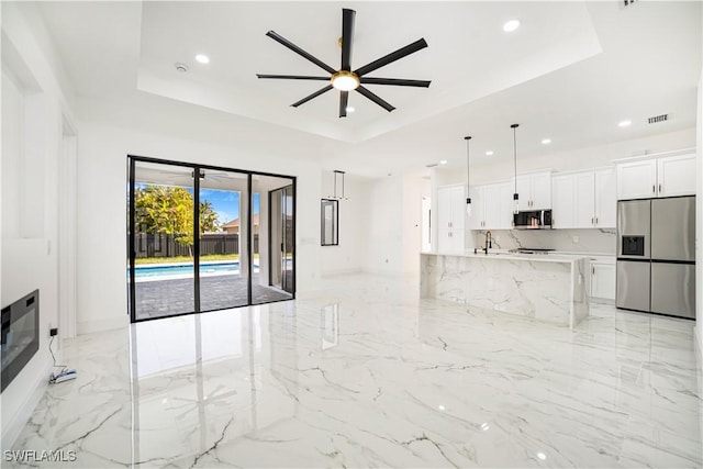 living room with ceiling fan, sink, and a tray ceiling