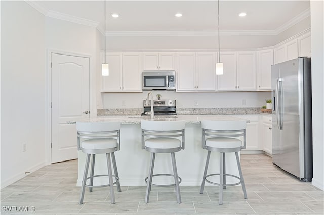 kitchen with white cabinets, appliances with stainless steel finishes, a center island with sink, and hanging light fixtures