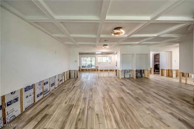 unfurnished living room with hardwood / wood-style floors, beamed ceiling, stacked washer / drying machine, and coffered ceiling