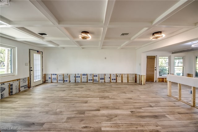 empty room with coffered ceiling, a healthy amount of sunlight, beamed ceiling, and light wood-type flooring