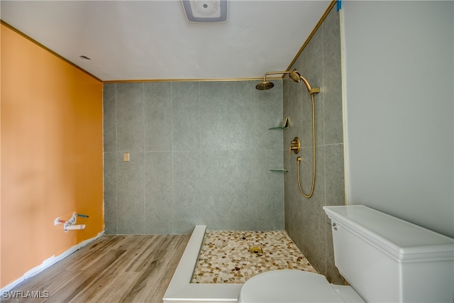 bathroom featuring toilet, wood-type flooring, and tiled shower