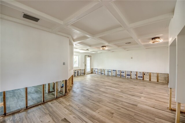 empty room featuring coffered ceiling, beamed ceiling, and light hardwood / wood-style flooring