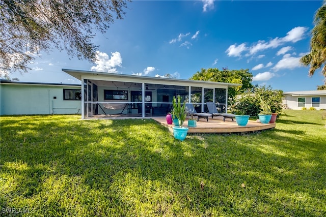 back of property featuring a deck, a yard, and a sunroom