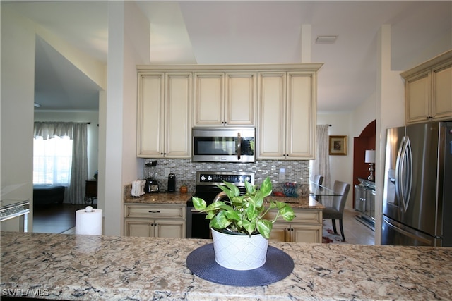 kitchen featuring light stone countertops, appliances with stainless steel finishes, and cream cabinetry