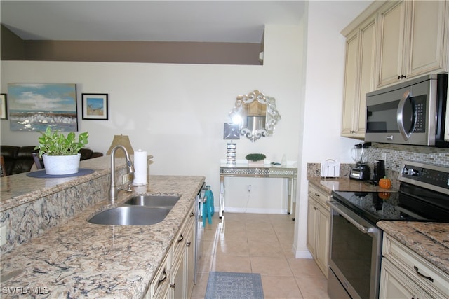 kitchen featuring sink, cream cabinetry, stainless steel appliances, light stone counters, and light tile patterned floors