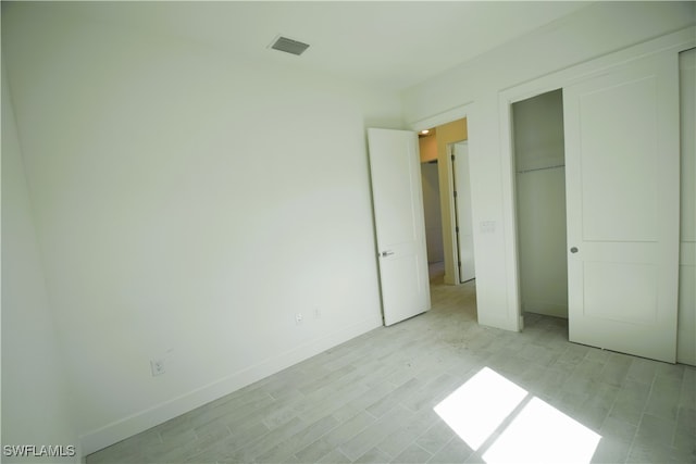 unfurnished bedroom with a closet and light hardwood / wood-style floors