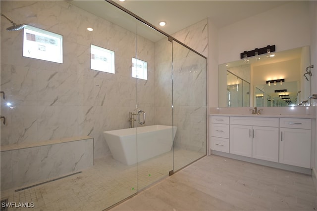 bathroom with tile walls, vanity, and shower with separate bathtub