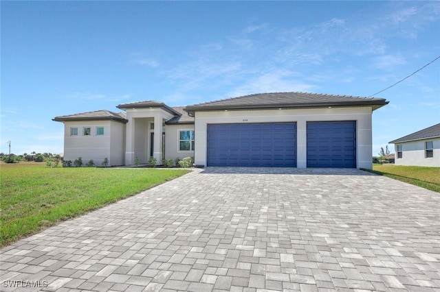 prairie-style house with an attached garage, a front yard, decorative driveway, and stucco siding