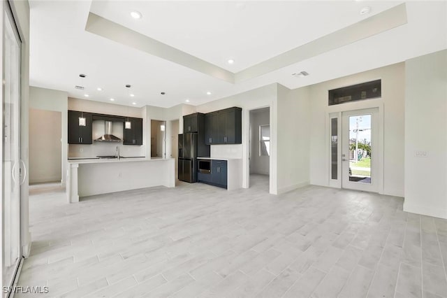 unfurnished living room featuring recessed lighting, a raised ceiling, visible vents, light wood-style flooring, and a sink