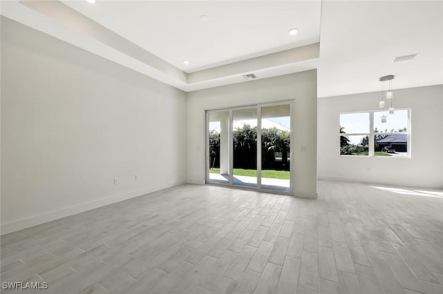 spare room featuring visible vents, baseboards, and wood finished floors