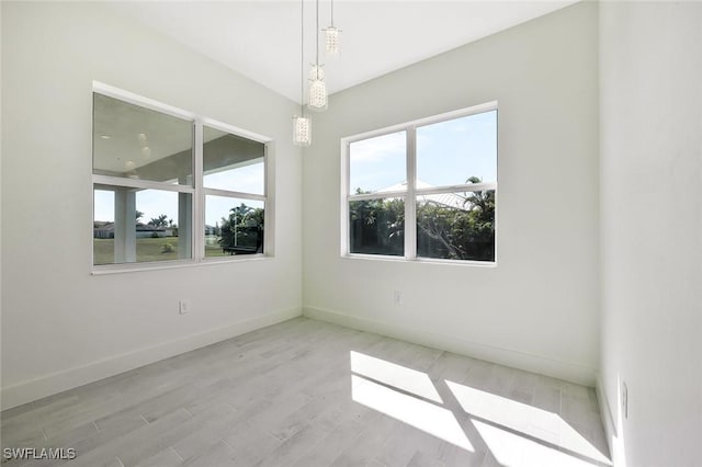 spare room with baseboards and wood finished floors