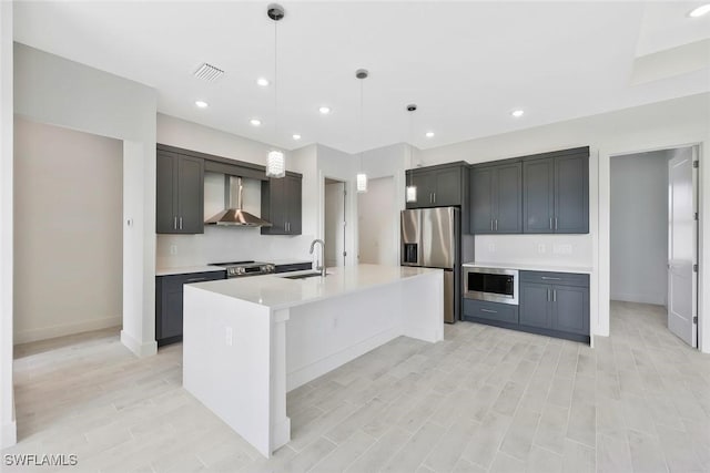 kitchen featuring stainless steel appliances, a sink, visible vents, light countertops, and wall chimney exhaust hood