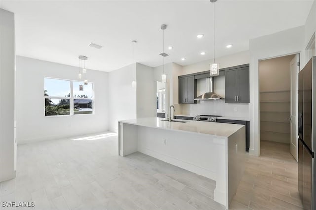 kitchen with light countertops, visible vents, a sink, range, and wall chimney exhaust hood