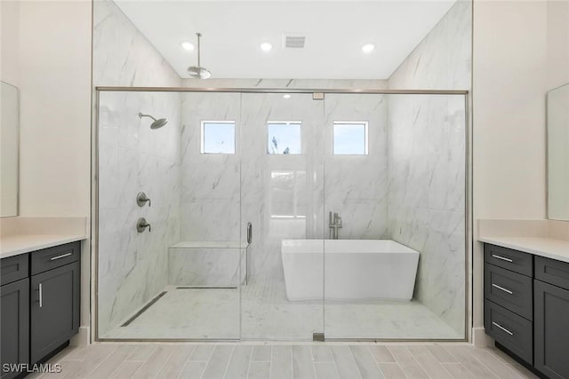 bathroom with a marble finish shower, visible vents, a freestanding bath, vanity, and a healthy amount of sunlight