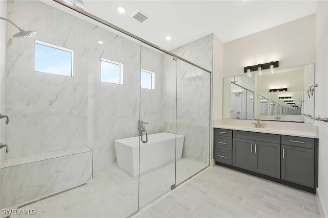 full bath featuring a marble finish shower, recessed lighting, a soaking tub, visible vents, and vanity