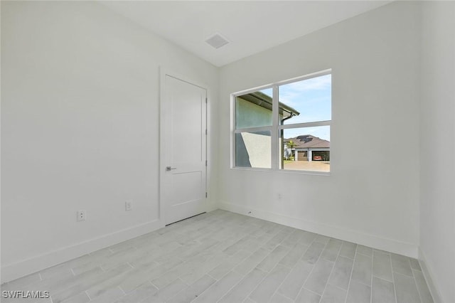 spare room with visible vents, light wood finished floors, and baseboards