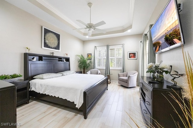 bedroom featuring ceiling fan, light hardwood / wood-style floors, ornamental molding, and a tray ceiling