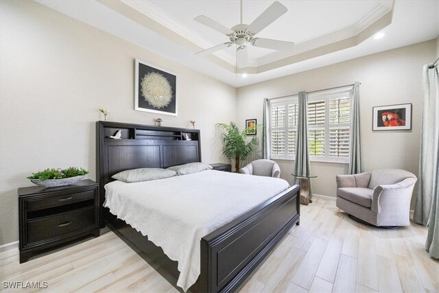 bedroom featuring light hardwood / wood-style flooring, a raised ceiling, ceiling fan, and ornamental molding