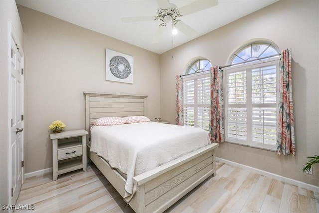 bedroom with a ceiling fan, baseboards, and light wood-style floors