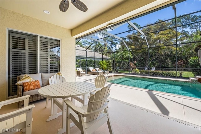 outdoor pool with a patio, ceiling fan, glass enclosure, and an outdoor hangout area
