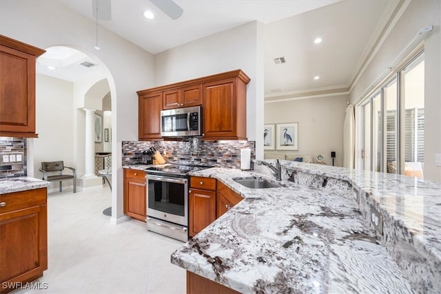 kitchen with ceiling fan, sink, light stone countertops, and appliances with stainless steel finishes