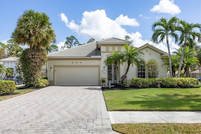 view of front facade featuring stucco siding, decorative driveway, a front yard, and a garage