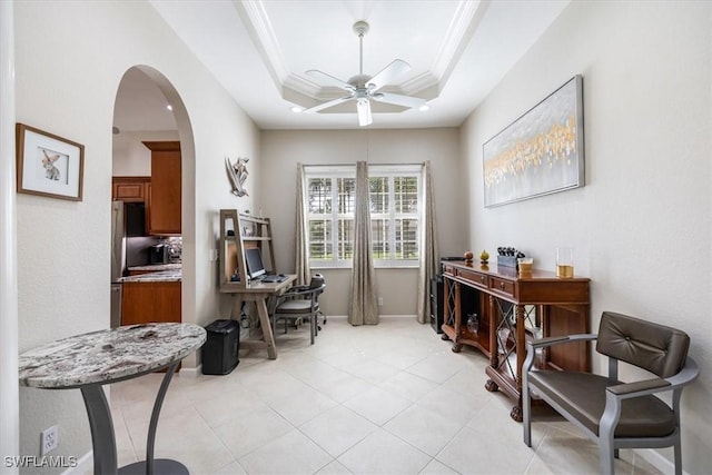 office with crown molding, arched walkways, a ceiling fan, light tile patterned floors, and a tray ceiling