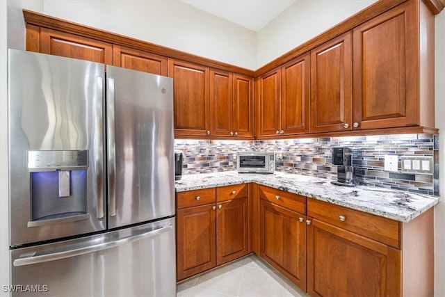 kitchen featuring decorative backsplash, stainless steel fridge, and light stone counters